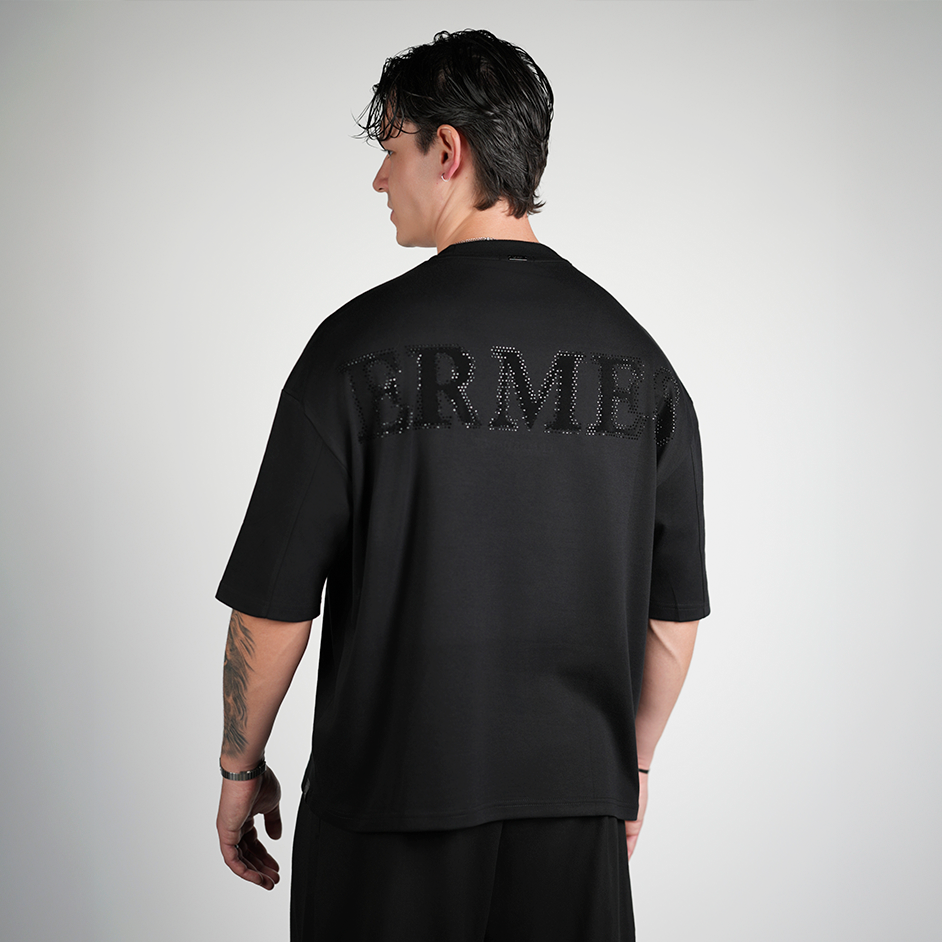 Person wearing a black t-shirt with 'ERMES' branding on the back against a gray background